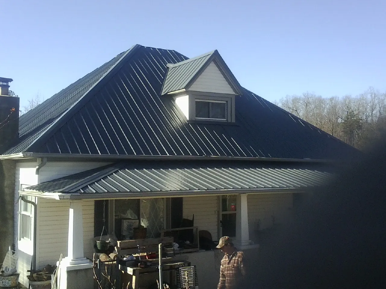 Dark blue standing seam metal roof with a dormer above a front porch in Springville