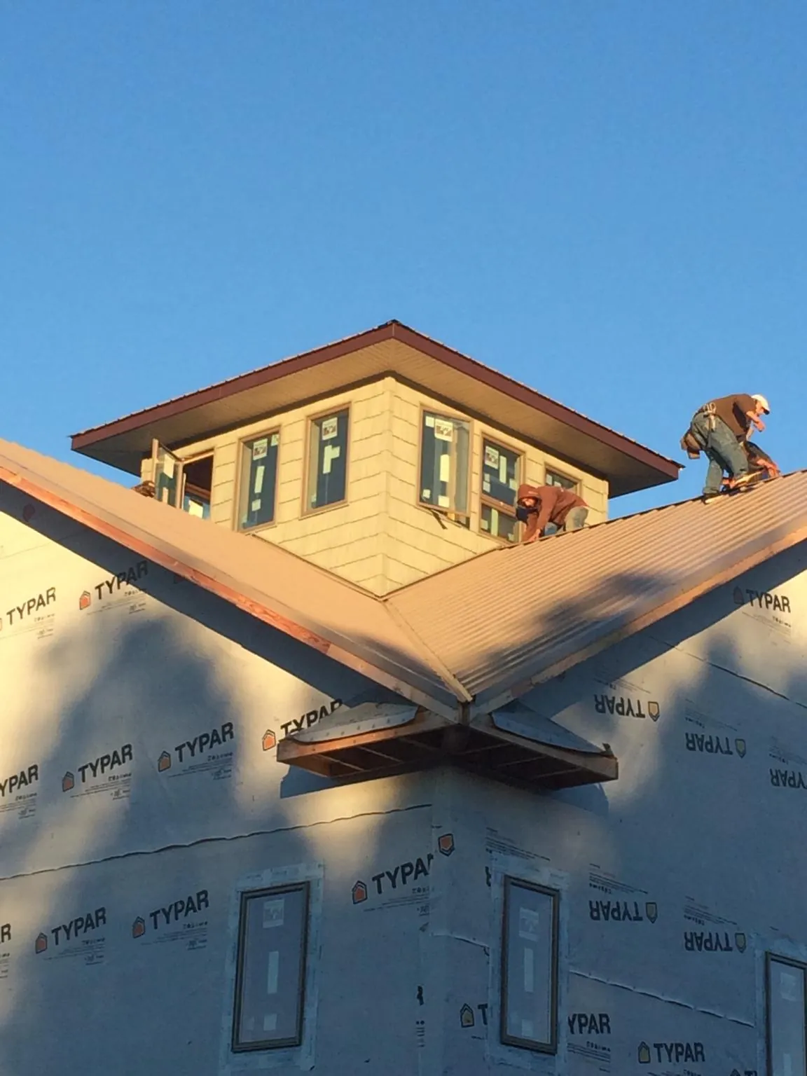 Roofers working around a rooftop cupola on a new metal roof at sunset — Roof Waterproofing in Springville by Roofing Brothers